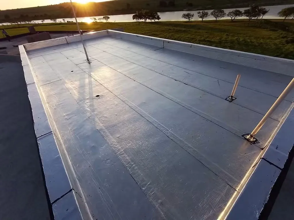Laje com manta asfáltica e ralos, com a represa e o pôr do sol ao fundo